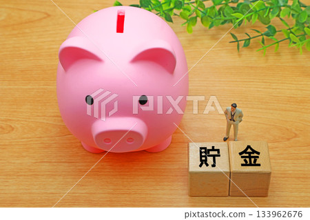 A block with the word "savings" written on it and a piggy bank 133962676