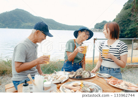 海灘上，三位家長和孩子們舉杯慶祝的場景 133962744