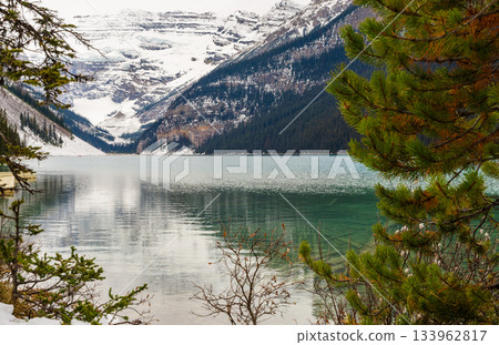 Tranquil Lake Louise with reflecting snow-capped mountain peaks and glacial slopes in crystal clear turquoise water in Banff National Park, Canada 133962817