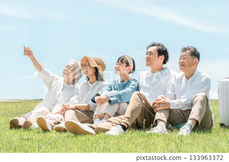 一個可以看到藍天的公園,一個坐在山上的家庭,父母和孩子,一個三代家庭(父親,母親,女兒,祖母,祖父) 一個可以看到藍天的公園,一個坐在山上的家庭,父母和孩子,一個三代家庭(父親,母親,女兒,祖母,祖父) 133963372
