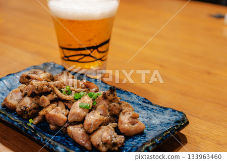 Enjoying yakitori and beer in the evening, Japanese snacks lined up on a wooden table Enjoying yakitori and beer in the evening, Japanese snacks lined up on a wooden table 133963460