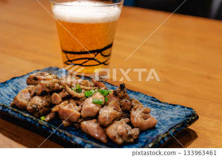 Enjoying yakitori and beer in the evening, Japanese snacks lined up on a wooden table 133963461