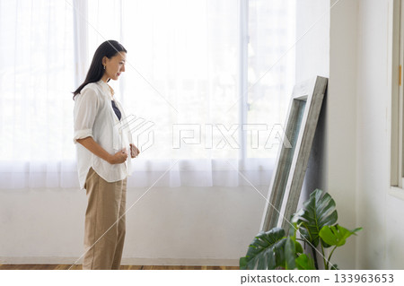 Middle-aged woman checking her outfit in front of the mirror Middle-aged woman checking her outfit in front of the mirror 133963653