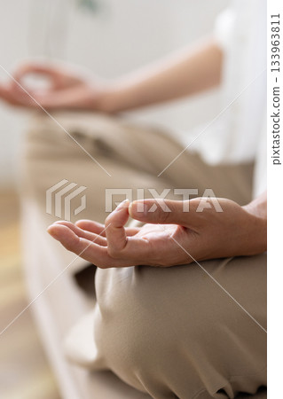 Close-up of a woman's hands meditating in a cross-legged position Close-up of a woman's hands meditating in a cross-legged position 133963811