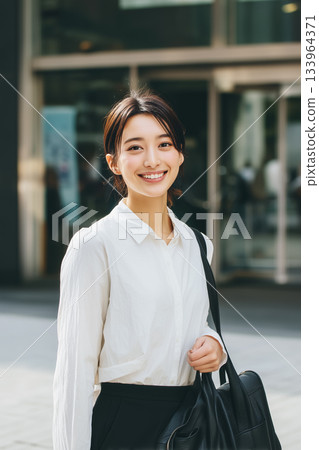 A young female employee smiling while out and about | A fresh and impressive business portrait A young female employee smiling while out and about | A fresh and impressive business portrait 133964371