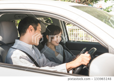 車內副駕駛座上的一男一女司機一邊開車一邊看著智慧型手機指路。 133965148