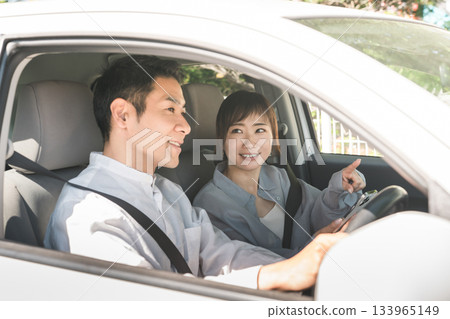 車內副駕駛座上的一男一女司機一邊開車一邊看著智慧型手機指路。 133965149