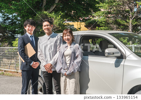 A young Asian male salesman serving customers who came to buy, assess and purchase a car A young Asian male salesman serving customers who came to buy, assess and purchase a car 133965154