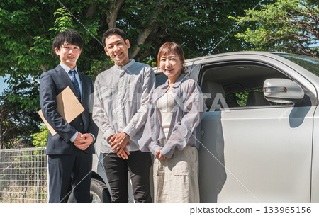 一位年輕的亞裔男性推銷員為前來選購、估價、購車的顧客服務。 133965156