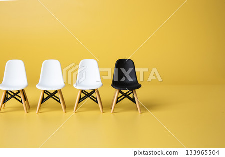 Black chair standing out from white chairs, representing diversity Black chair standing out from white chairs, representing diversity 133965504