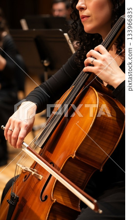 Close up of a female cellist playing the cello in an orchestra. Vertical photo of a musician performing classical music on stage with selective focus Close up of a female cellist playing the cello in an orchestra. Vertical photo of a musician performing classical music on stage with selective focus 133966835