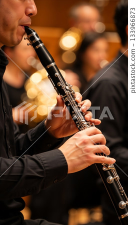Close up of a male musician playing the clarinet in an orchestra. Vertical photo of professional artist performing classical music concert 133966873