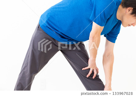A middle-aged man in a T-shirt doing leg stretching exercises 133967028