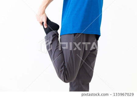 A middle-aged man in a T-shirt doing leg stretching exercises A middle-aged man in a T-shirt doing leg stretching exercises 133967029