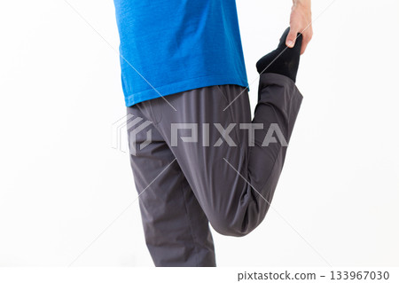 A middle-aged man in a T-shirt doing leg stretching exercises A middle-aged man in a T-shirt doing leg stretching exercises 133967030