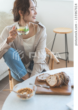 一位年輕的亞洲女性正在餐桌旁吃早餐。 133967814