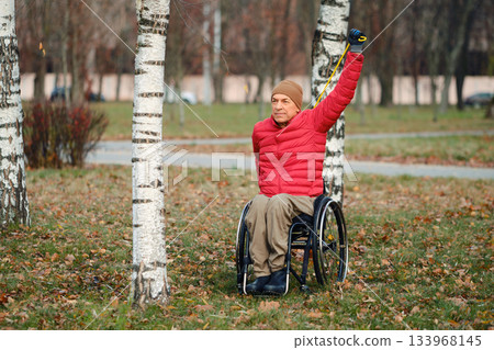 Enjoying the outdoors and exercising in a park while using a wheelchair during a sunny autumn day Enjoying the outdoors and exercising in a park while using a wheelchair during a sunny autumn day 133968145