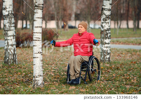 Individual in wheelchair enjoying outdoor stretch in park during autumn season Individual in wheelchair enjoying outdoor stretch in park during autumn season 133968146