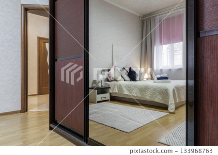 Mirror Wardrobe View into Cozy Bedroom with Soft Lighting and Neutral Decor Mirror Wardrobe View into Cozy Bedroom with Soft Lighting and Neutral Decor 133968763