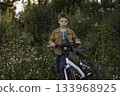 cute caucasian boy cycling on the glade of fireweed in countryside 133968925