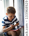 boy sitting on window drawing og graphic pad 133968929