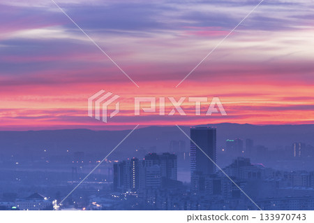 A breathtaking and stunning sunset beautifully paints the sky in vibrant hues above a modern city skyline, Krasnoyarsk evening city at sunset panorama. A breathtaking and stunning sunset beautifully paints the sky in vibrant hues above a modern city skyline, Krasnoyarsk evening city at sunset panorama. 133970743