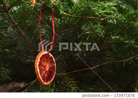 Closeup christmas tree with dried orange hanging on it Closeup christmas tree with dried orange hanging on it 133971878