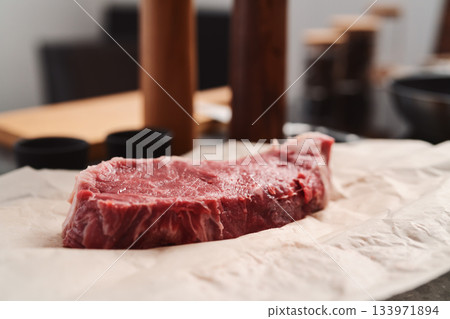 Raw new york sirloin steak on parchment paper warming up before cooking Raw new york sirloin steak on parchment paper warming up before cooking 133971894