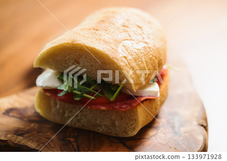 ciabatta sandwich with salami and mozzarella cheese on walnut table ciabatta sandwich with salami and mozzarella cheese on walnut table 133971928