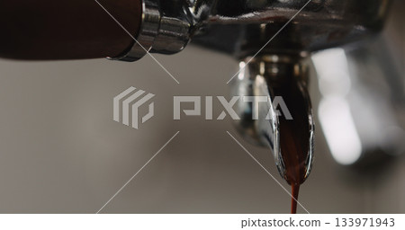 pulling espresso shot with single spout portafilter from coffee machine closeup pulling espresso shot with single spout portafilter from coffee machine closeup 133971943