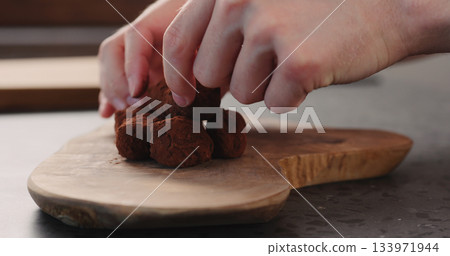 man hand put handmade chocolate truffles on a wood board man hand put handmade chocolate truffles on a wood board 133971944