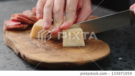 man slicing parmesan hard cheese on olive wood board man slicing parmesan hard cheese on olive wood board 133971959