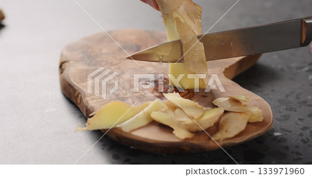 man hands peeling fresh ginger root with knife on olive wood board man hands peeling fresh ginger root with knife on olive wood board 133971960
