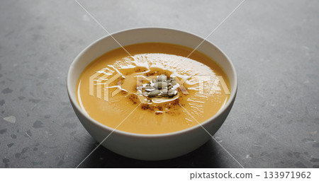 closeup pumpkin cream soup in white bowl on terrazzo countertop closeup pumpkin cream soup in white bowl on terrazzo countertop 133971962