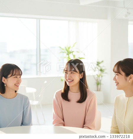 陽光柔和地灑在現代風格的白色辦公室裡，一位年輕的女上班族正在聊天。 133972218