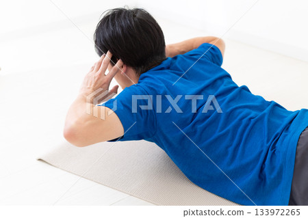 一名身穿T恤的中年男子正在進行背部肌肉訓練 一名身穿T恤的中年男子正在進行背部肌肉訓練 133972265