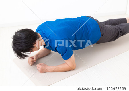 一名身穿T恤的中年男子正在做平板支撐練習 133972269