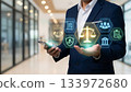 Businessman hand holding smartphone with legal justice icons and balance scale hologram. 133972680