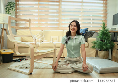 Young woman smiling after assembling furniture in modern living room, DIY home project 133972781