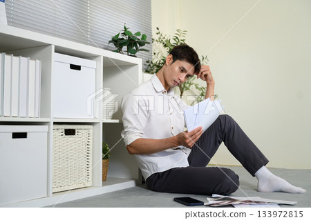 Stressed young man holding so many expenses bills in his hand no money to pay debt Stressed young man holding so many expenses bills in his hand no money to pay debt 133972815