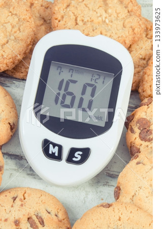 Glucose meter with high sugar level and cookies Glucose meter with high sugar level and cookies 133973625