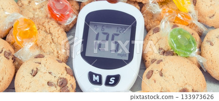 Glucose meter with high sugar level, candies and cookies 133973626