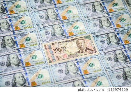一張傾斜的100美元鈔票的特寫鏡頭,畫面中心是一張10000日元鈔票。 一張傾斜的100美元鈔票的特寫鏡頭,畫面中心是一張10000日元鈔票。 133974369