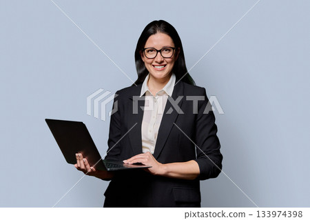 Portrait of successful middle-aged businesswoman with laptop on light background 133974398