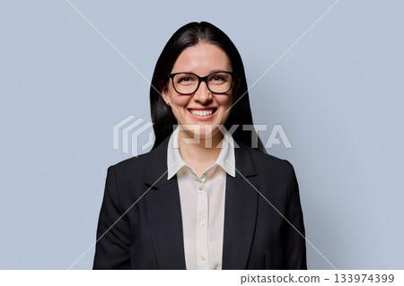 Portrait of smiling middle-aged businesswoman in black jacket on light studio background 133974399