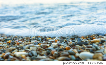Sea wave rolling over colorful pebbles on the shore Sea wave rolling over colorful pebbles on the shore 133974507