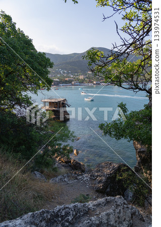 Coast of Novy Svet at sunrise with the mountain, sea, and recreational boats Coast of Novy Svet at sunrise with the mountain, sea, and recreational boats 133974531