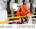 Technician monitor and command by radio to operator on job site in oil and gas industry, Worker in oil and gas industry contact to operation team to check condition of the machine. 133975833