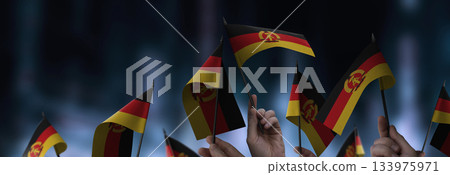 GDR flags in their hands on a blurred urban background 133975971