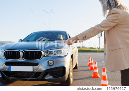 Driving Instructor Pointing Toward Car During Training Session with Cones Driving Instructor Pointing Toward Car During Training Session with Cones 133976617